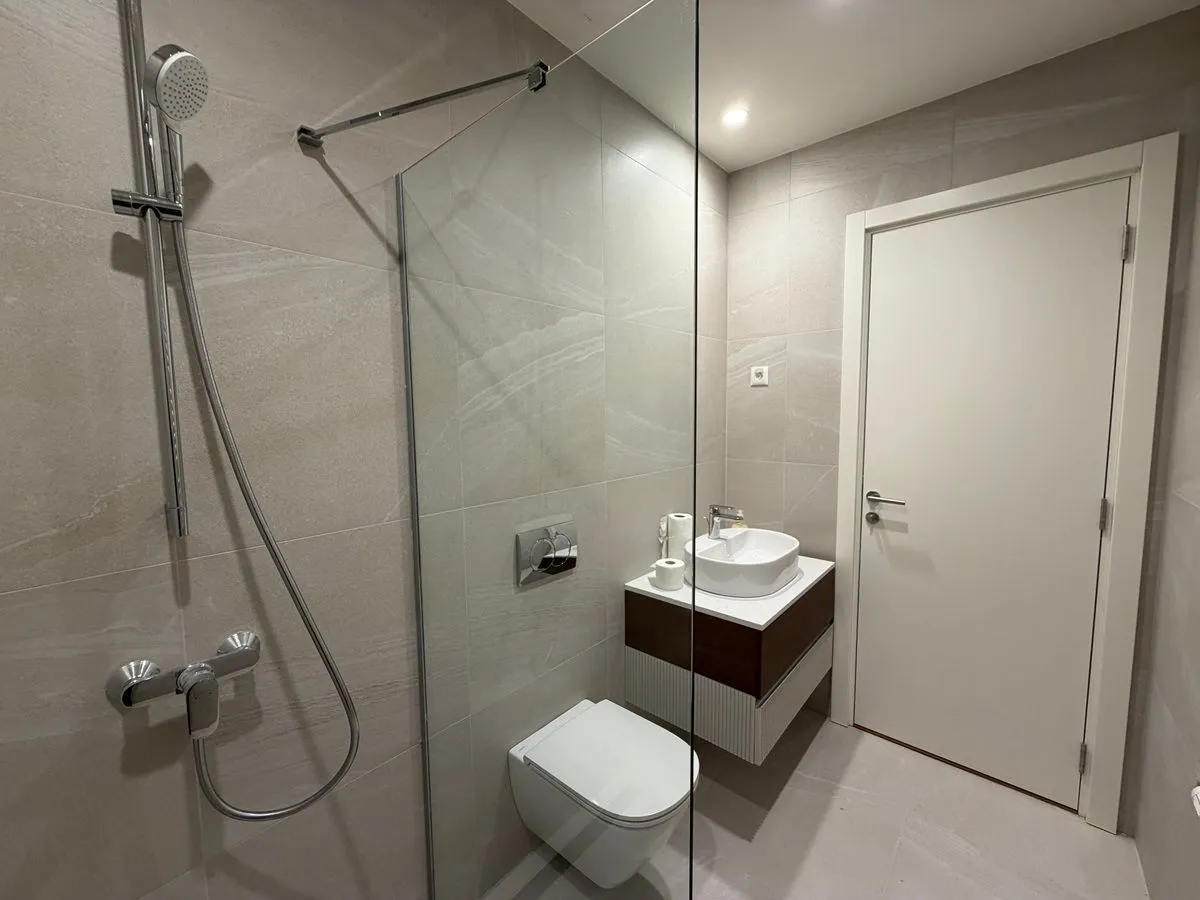Moderno kupatilo sa tuš kabinom, umivaonikom i ugradnom wc šoljom.