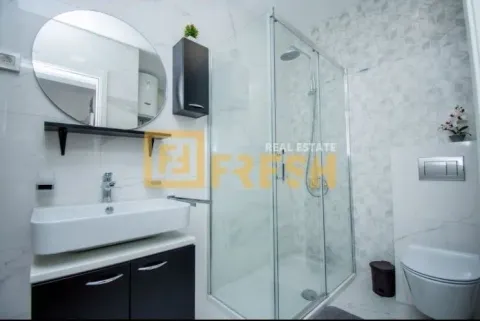 Modern bathroom with a shower cabin, sink, and a round mirror. - image 7