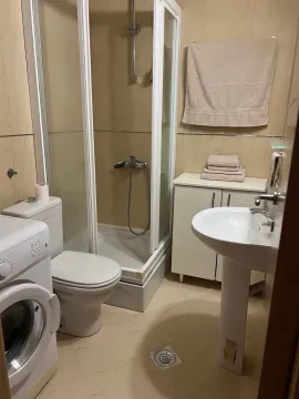 Smaller bathroom with a shower cabin, washbasin, and washing machine. - image 8