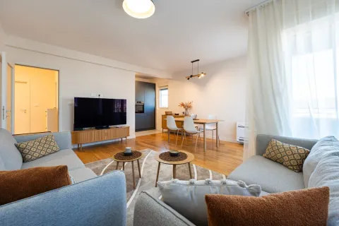 Spacious living room with seating area, television, and dining space in the background. - image 3