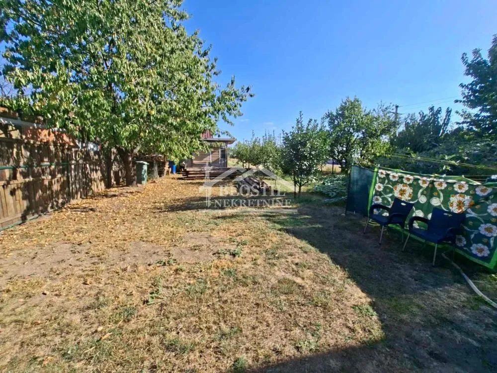 Pogled na prostrano dvorište sa travnjakom i drvećem.