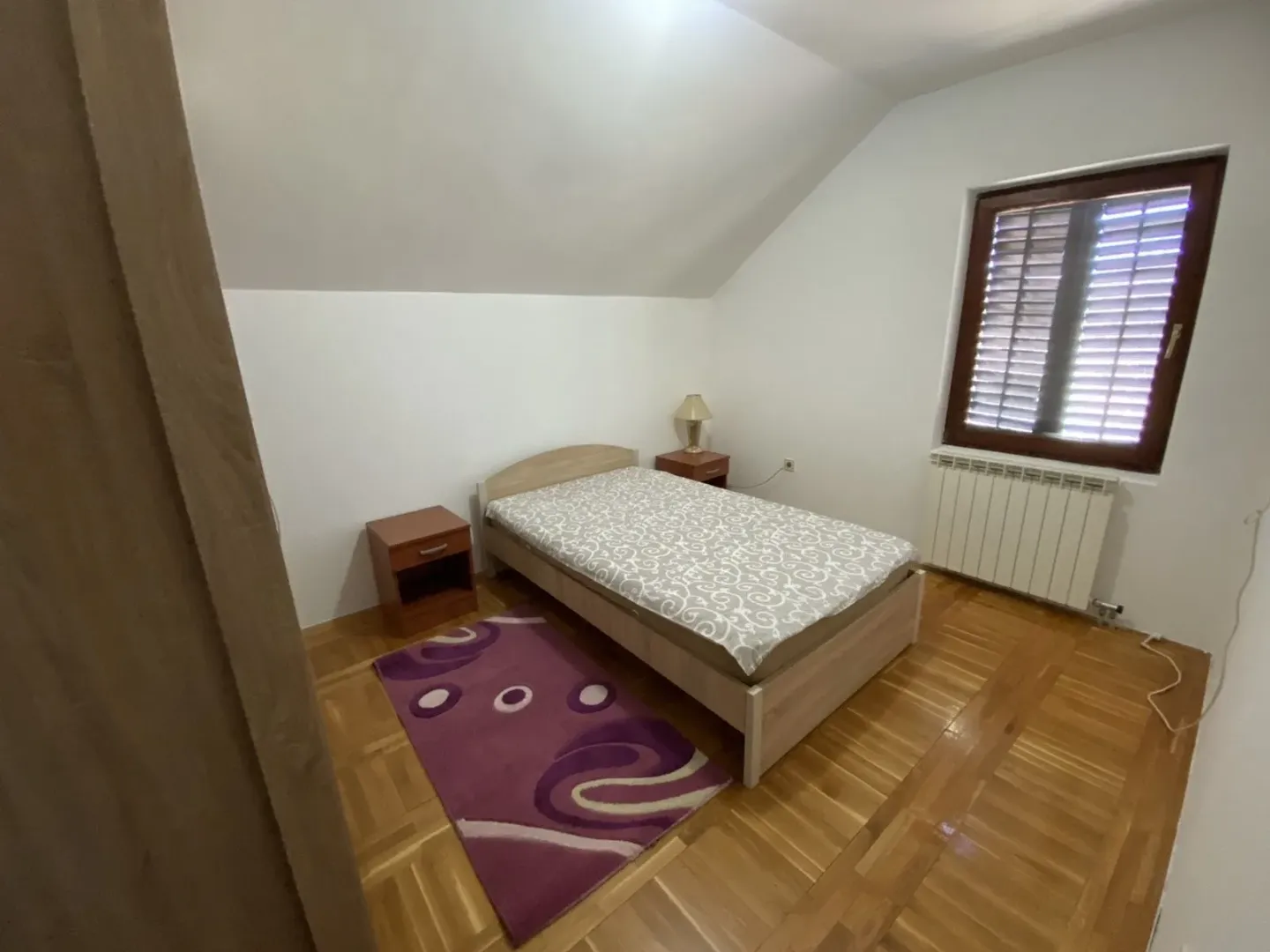 Simple bedroom with a sloped ceiling and a single bed.