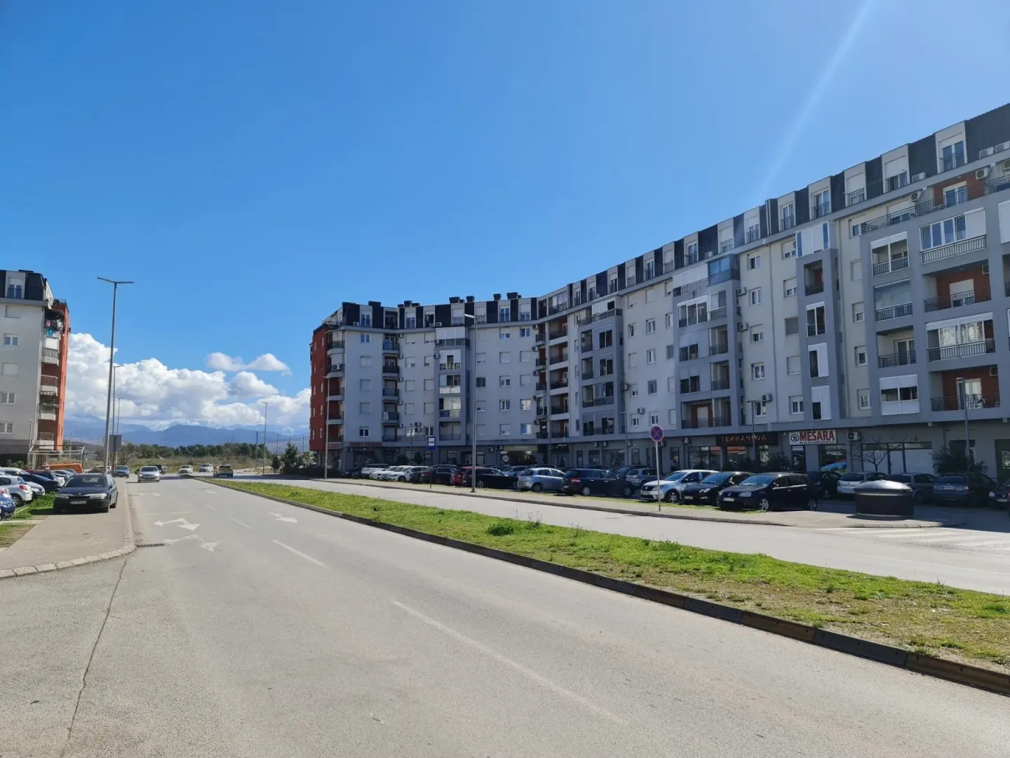 Exterior of a multi-story residential building with parking and a street in front.