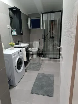 Modern bathroom with a shower cabin, sink, and washing machine. - image 15