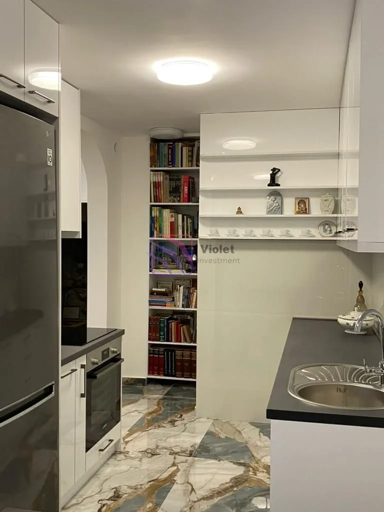 Moderna bijela kuhinja sa sudoperom, rernom i ugradnim elementima.