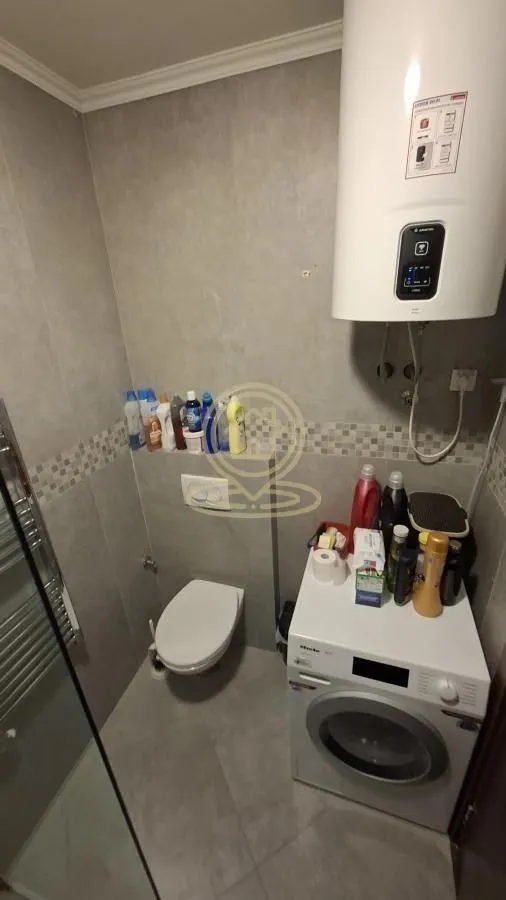 Manje kupatilo sa tuš kabinom, WC šoljom, veš mašinom i bojlerom.
