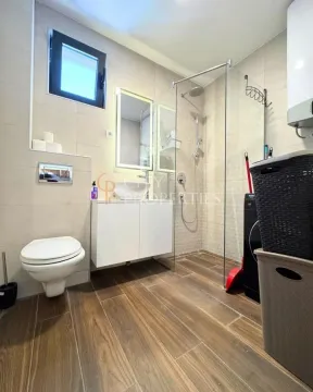 Modernly equipped bathroom with a walk-in shower, washbasin, and toilet. - image 5