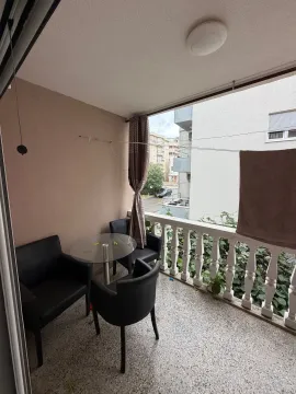 Natkrivena terasa sa garniturom za sedenje i pogledom na okolne zgrade. - image 7