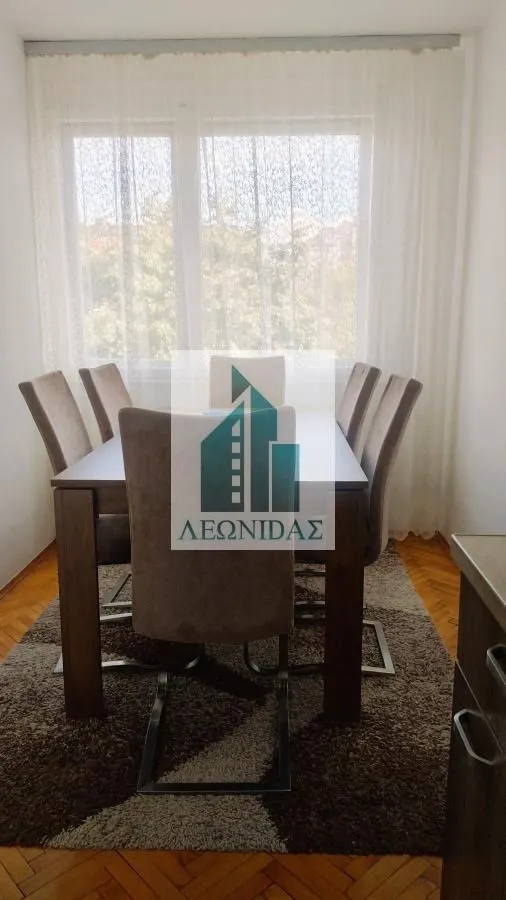 Dining area with a wooden table and upholstered chairs by the window.