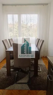 Dining area with a wooden table and upholstered chairs by the window. - image 5