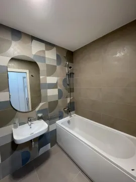 Bathroom with a bathtub, washbasin, and mirror. - image 8