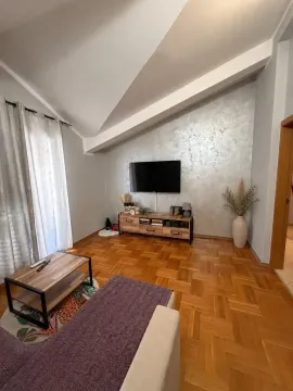 Living room with a sofa, TV, and parquet flooring. - image 3