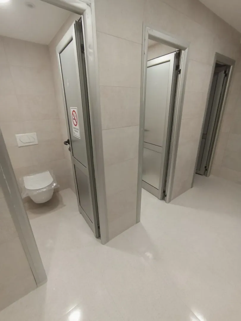 Shared restroom with multiple stalls in a new building.