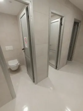 Shared restroom with multiple stalls in a new building. - image 11