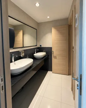 Modern bathroom with double sinks and a large mirror. - image 16