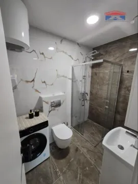 Moderno opremljeno kupatilo sa tuš kabinom, umivaonikom, veš mašinom i WC šoljom. - image 11