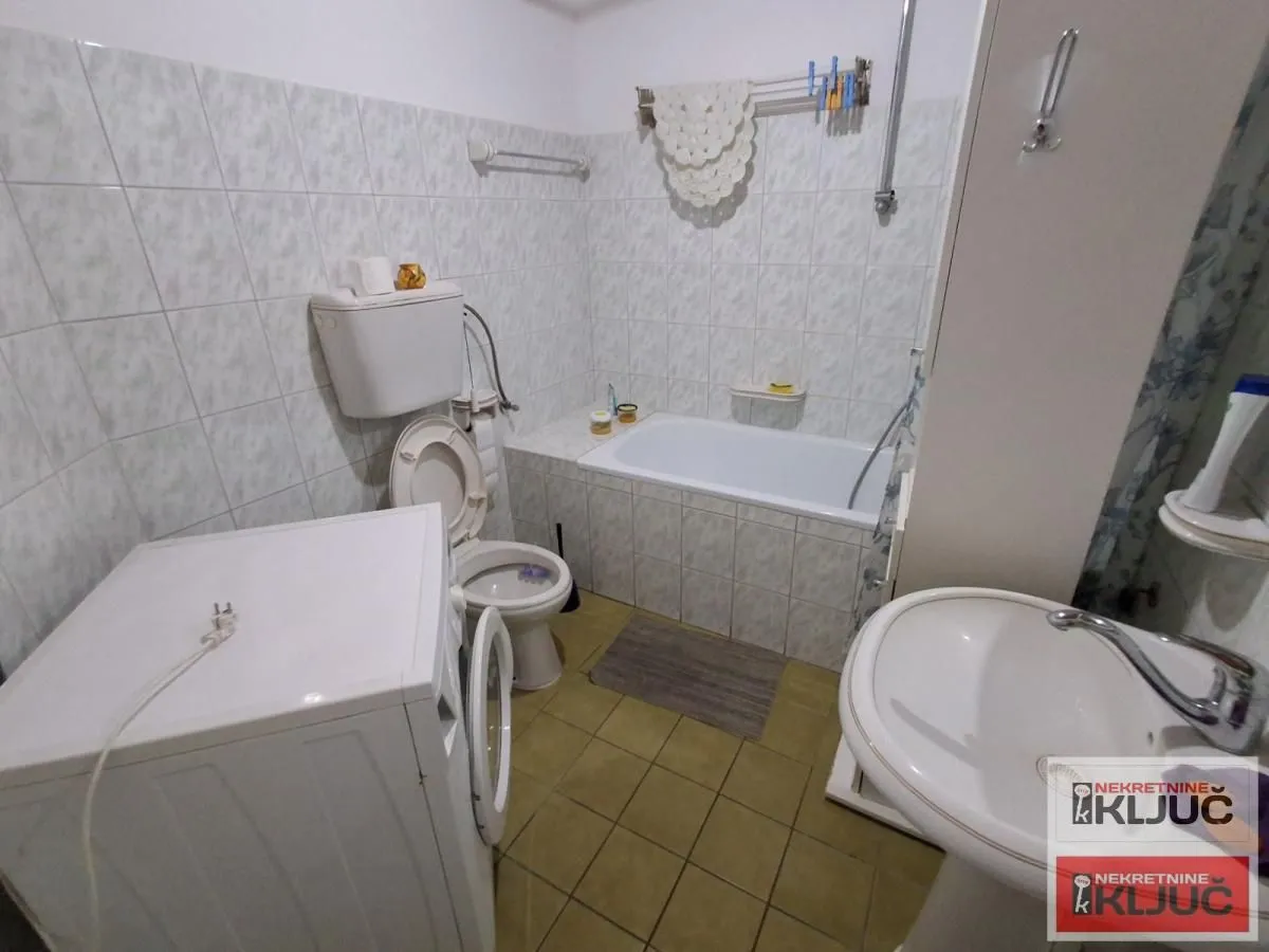 Kupatilo opremljeno kadom, umivaonikom, WC šoljom i veš mašinom.
