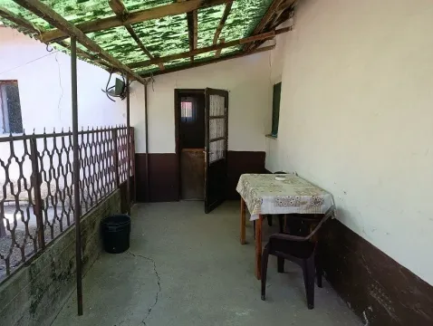 Natkrivena terasa ispred ulaza u kuću sa stolom i stolicama. - image 4