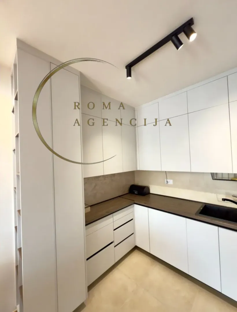 Modern white kitchen with dark countertops and built-in units.