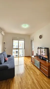 Living room with a sofa, TV cabinet, and hardwood flooring. - image 3