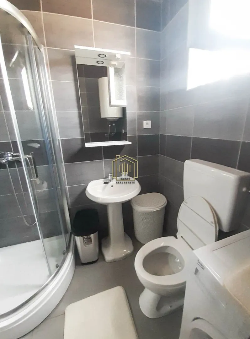 Compact bathroom with a shower cabin, washbasin, toilet, and mirror.