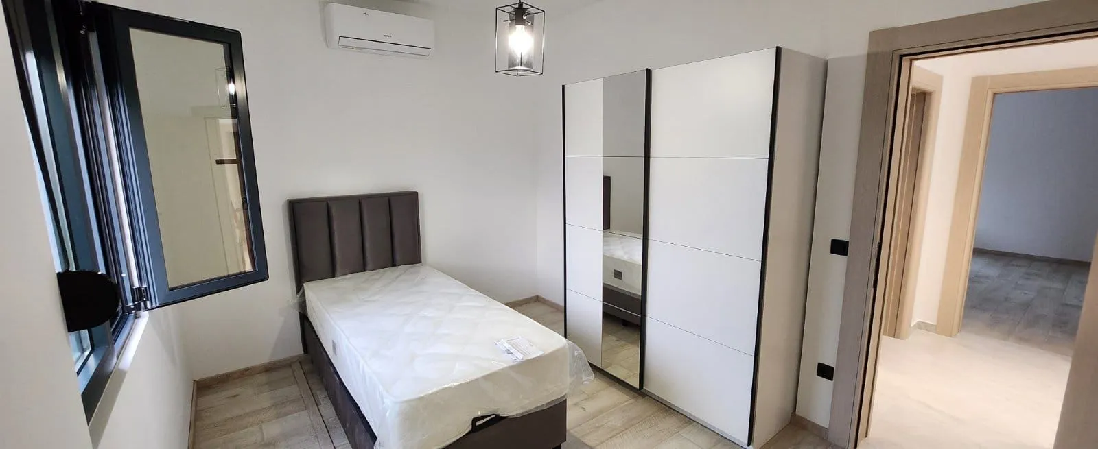 Svijetla spavaća soba sa krevetom i bijelim garderoberom.