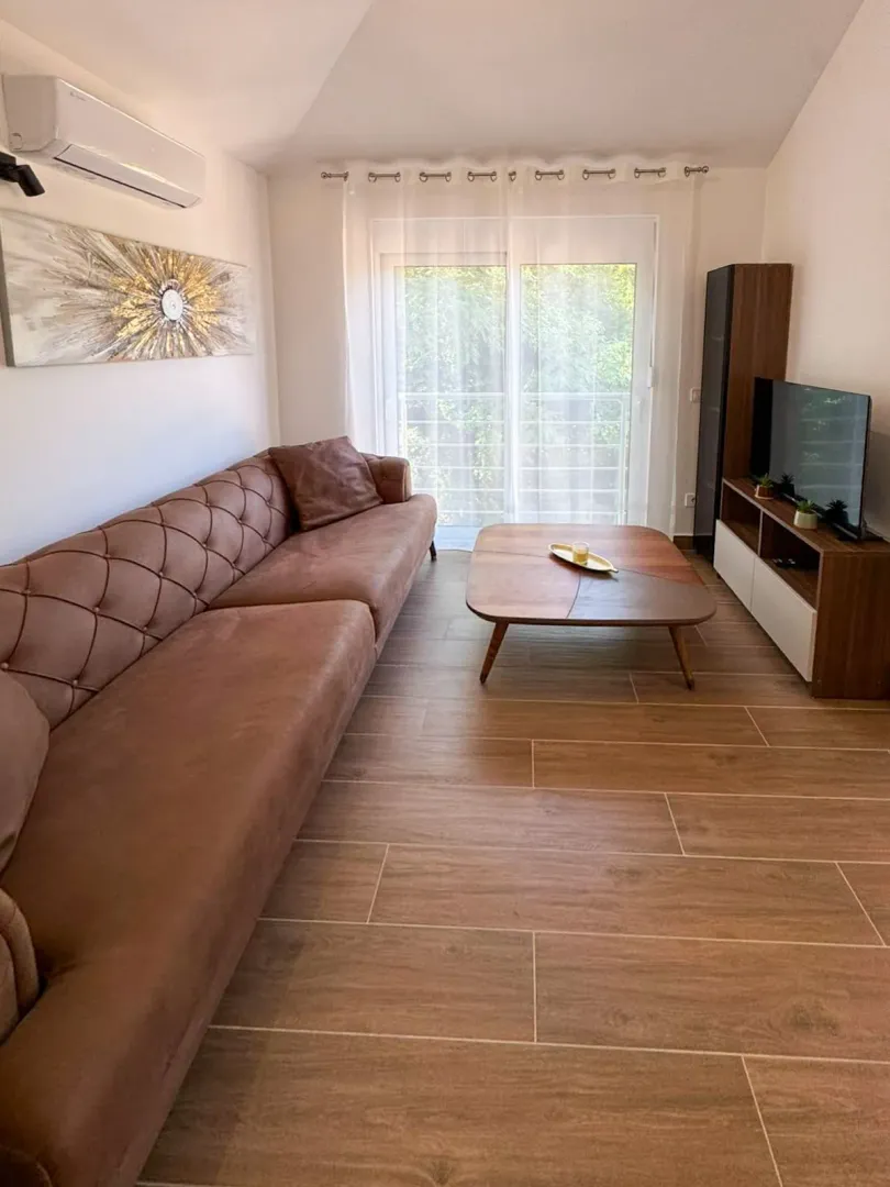 Living room with a brown sofa, wooden coffee table, and a TV.