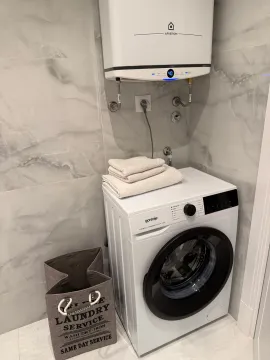 Bathroom with a washing machine, water heater, and laundry basket. - image 6