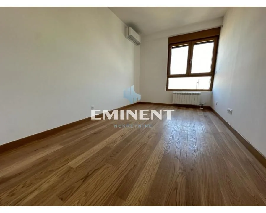 Empty room with wooden flooring and a window.