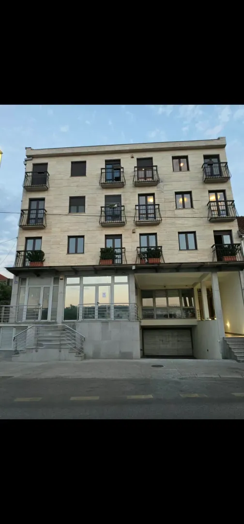 Front facade of a multi-story residential building with balconies and ground floor garage.