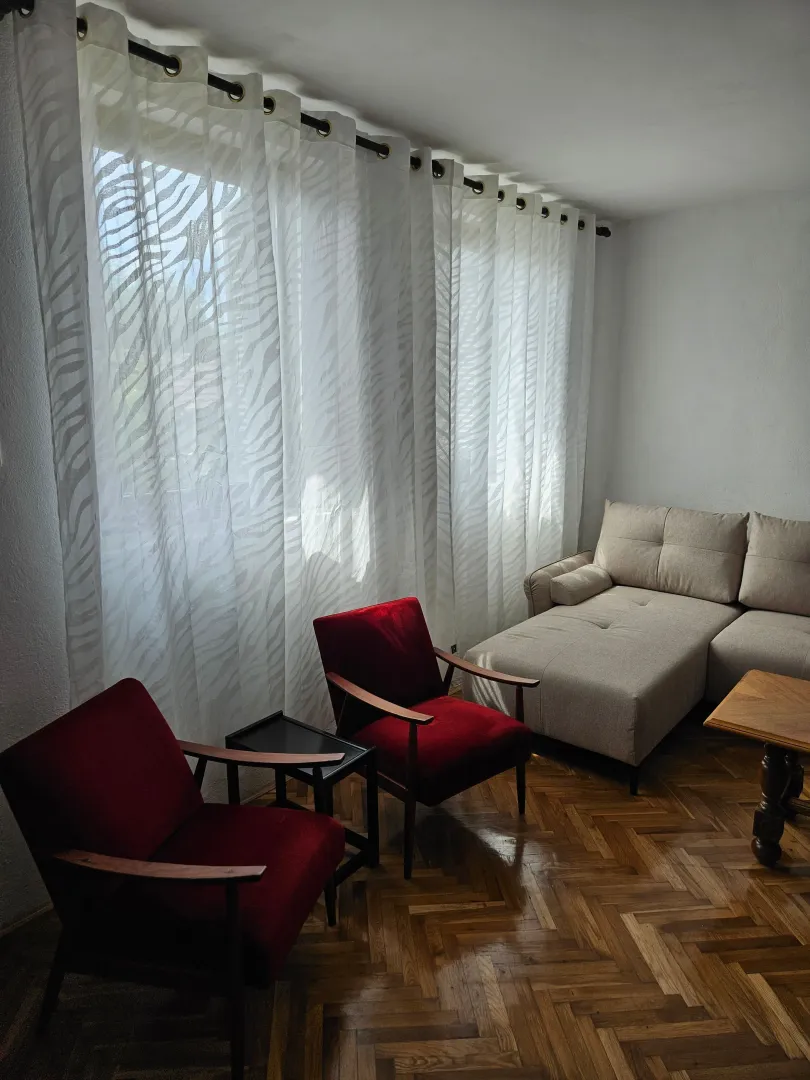 Living room with a sofa, armchairs, and parquet flooring.