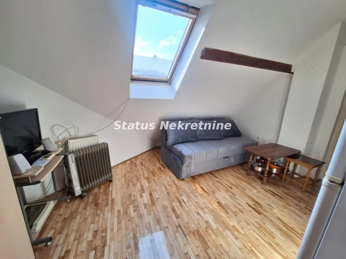 Attic living space with a sofa, coffee table and a skylight.