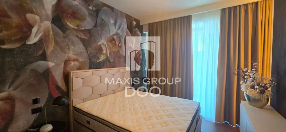 Furnished bedroom with a double bed and a patterned wall.