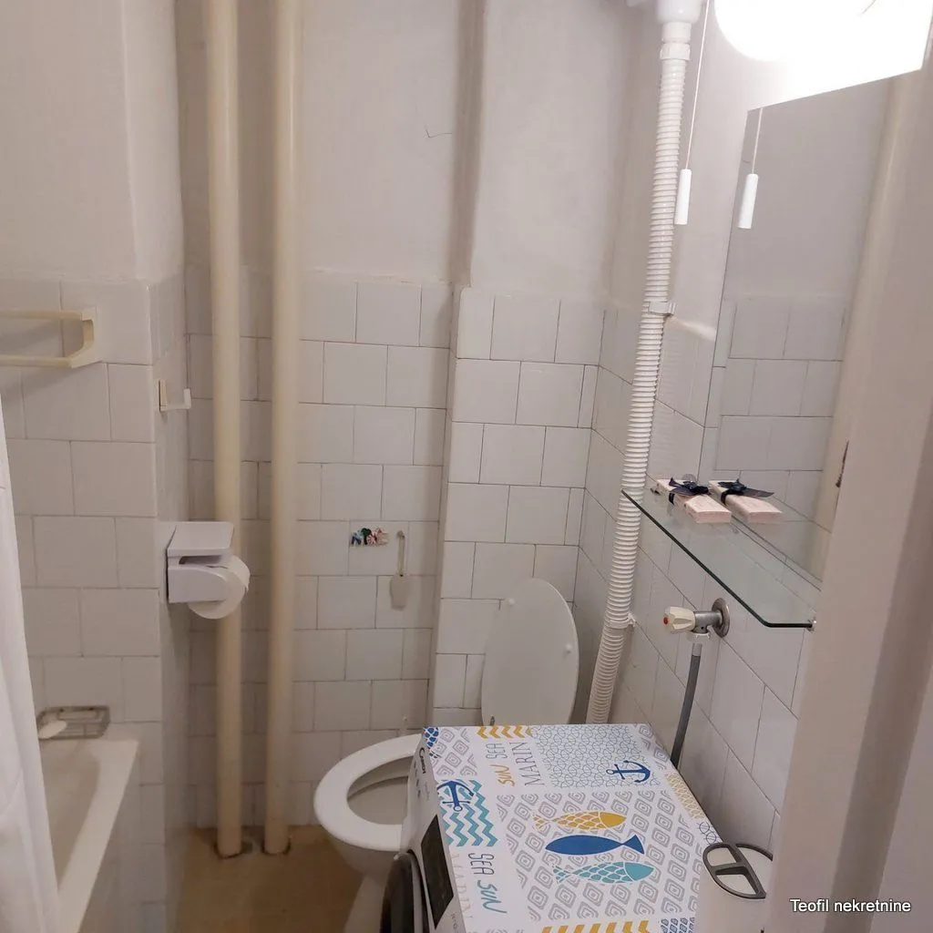 Manje kupatilo sa kadom, toaletom i mašinom za veš.