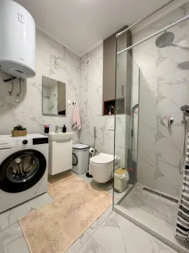 Modern bathroom with a walk-in shower, washbasin, and washing machine. - image 8