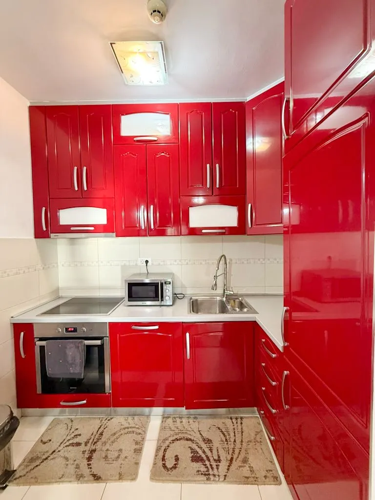Kitchen with bright red cabinets, built-in oven, sink, and countertop.