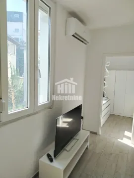 Dnevni boravak sa televizorom na komodi i klima uređajem na zidu. - image 3