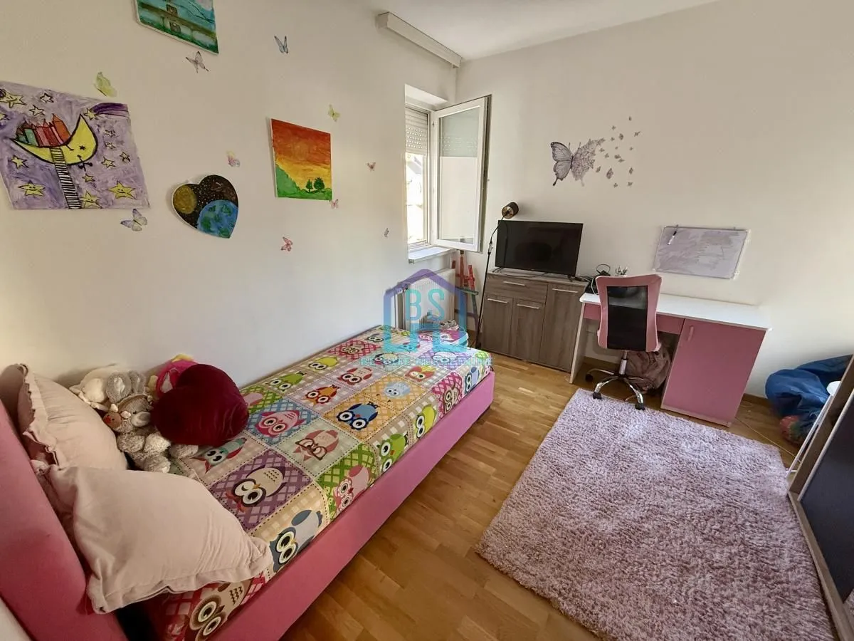 Dečja spavaća soba sa krevetom, radnim stolom i dečjim ukrasima na zidu.