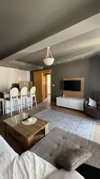 Spacious living room with sofa, TV and kitchen in the background. - image 6