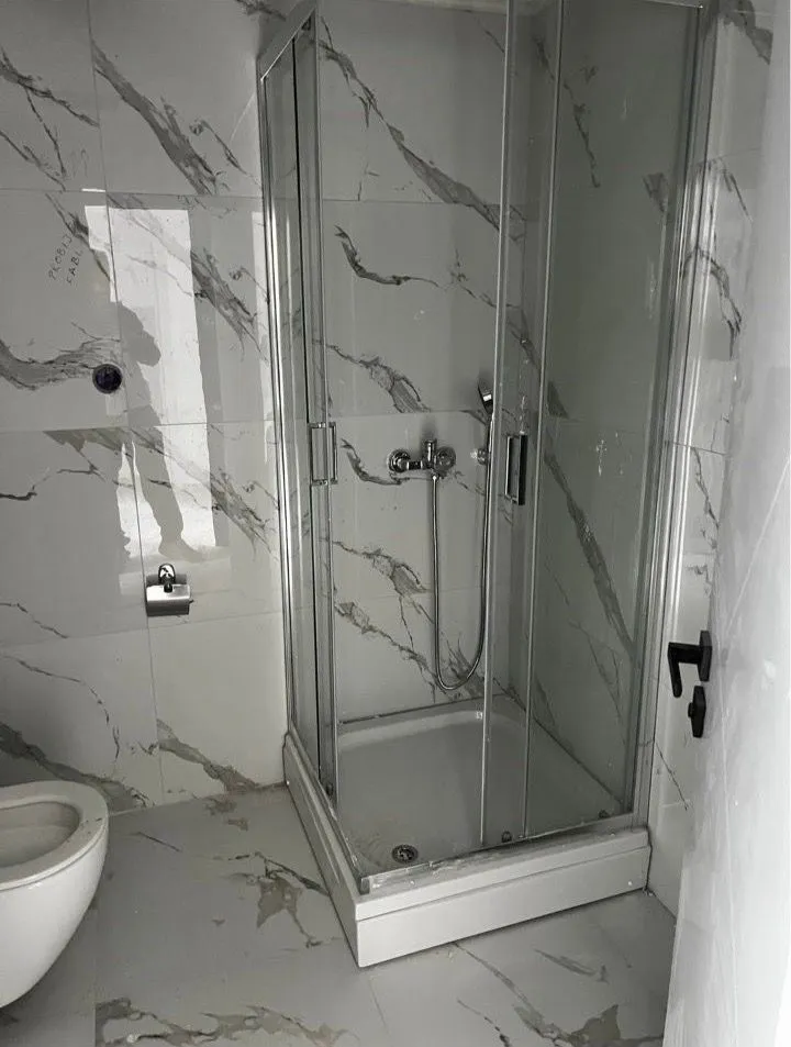 Newly equipped bathroom with a shower cabin and marble tiles.