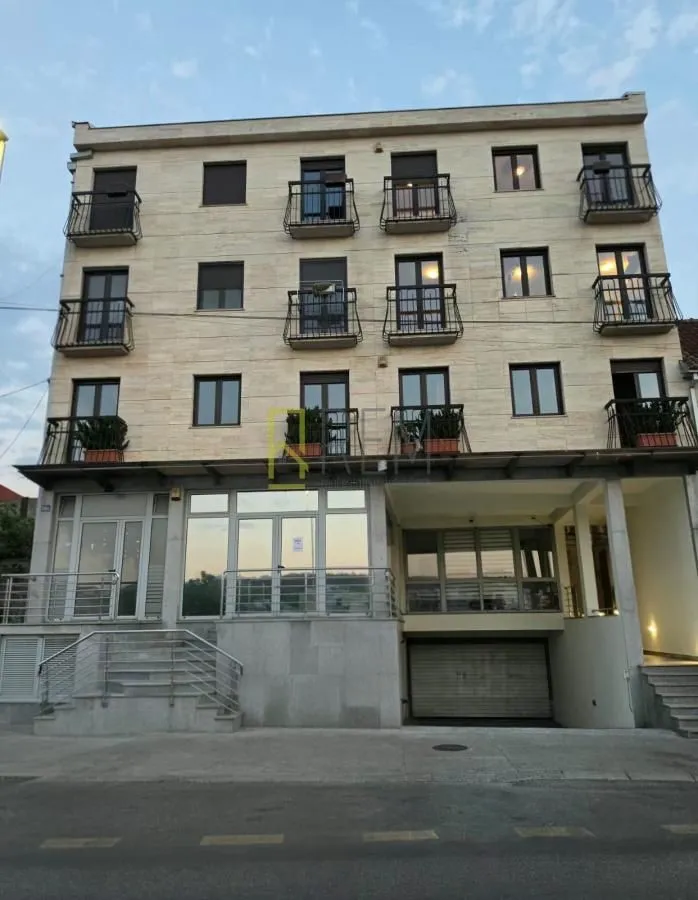 View of the multi-family residential building facade with balconies and ground-floor commercial space.