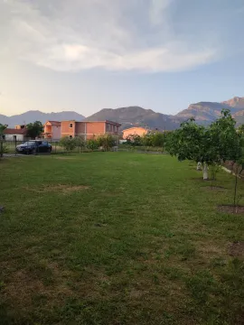 Prostrano travnato dvorište sa pogledom na okolne kuće i planine. - image 7