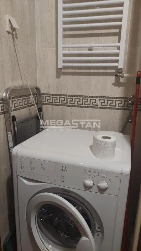 View of the bathroom with a washing machine and a towel radiator.