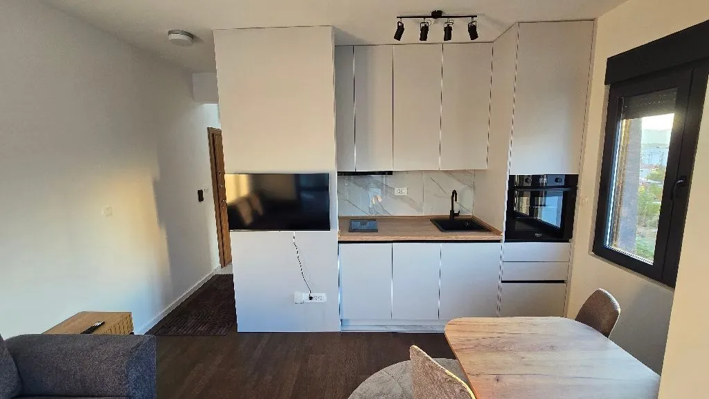 Modern kitchen with white cabinetry and a built-in oven integrated into the living area.