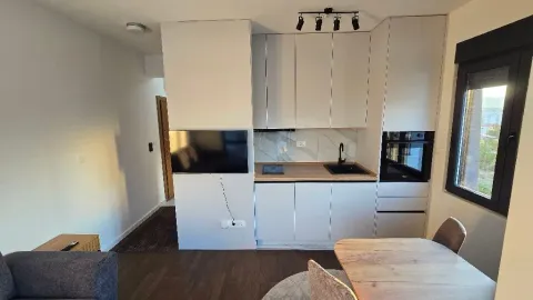 Modern kitchen with white cabinetry and a built-in oven integrated into the living area. - image 14