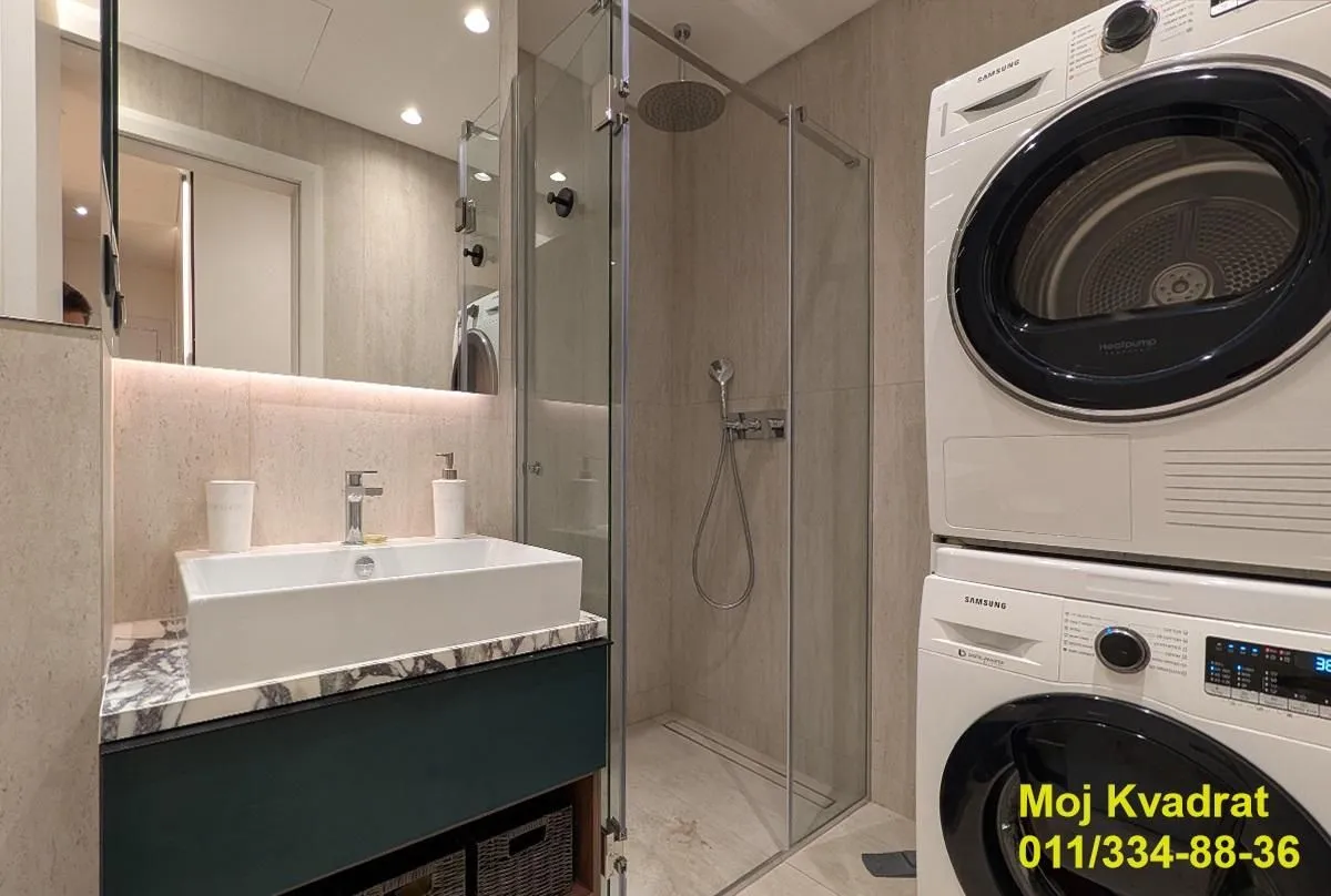 Modern bathroom with a shower cabin and stacked washing and drying machine.
