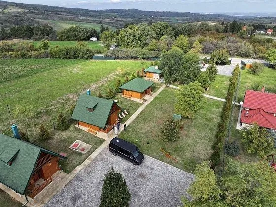 Pogled iz vazduha na kompleks drvenih kućica sa uređenim dvorištem i zelenilom.