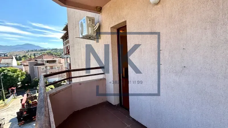 Manji balkon sa metalnom ogradom i pogledom na naselje.