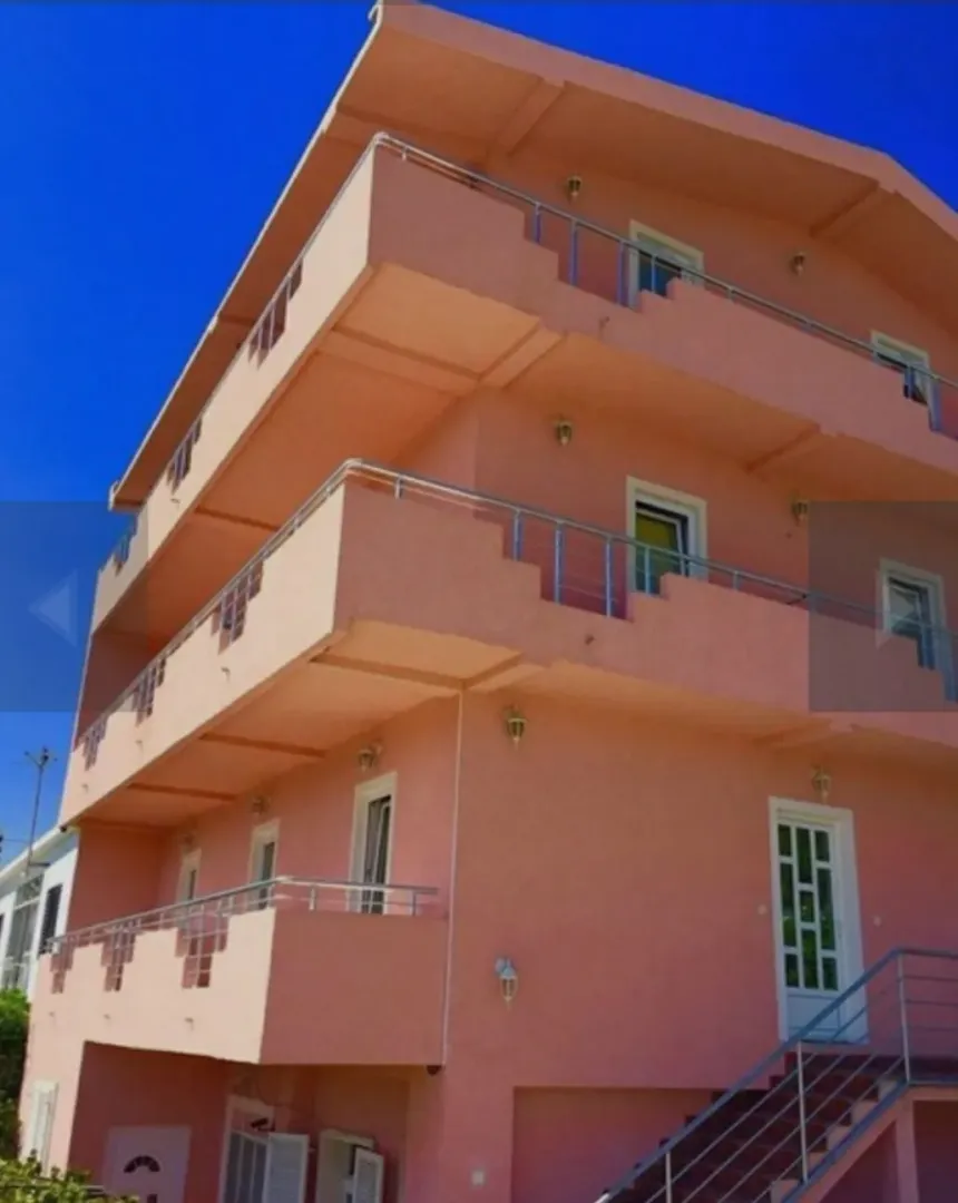 Exterior view of a multi-story pink residential building with balconies.