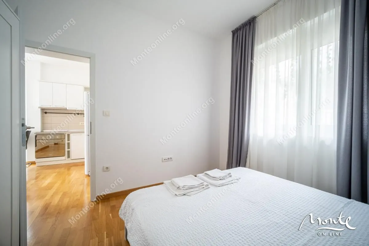 Bright bedroom with a double bed and a view into the kitchen.